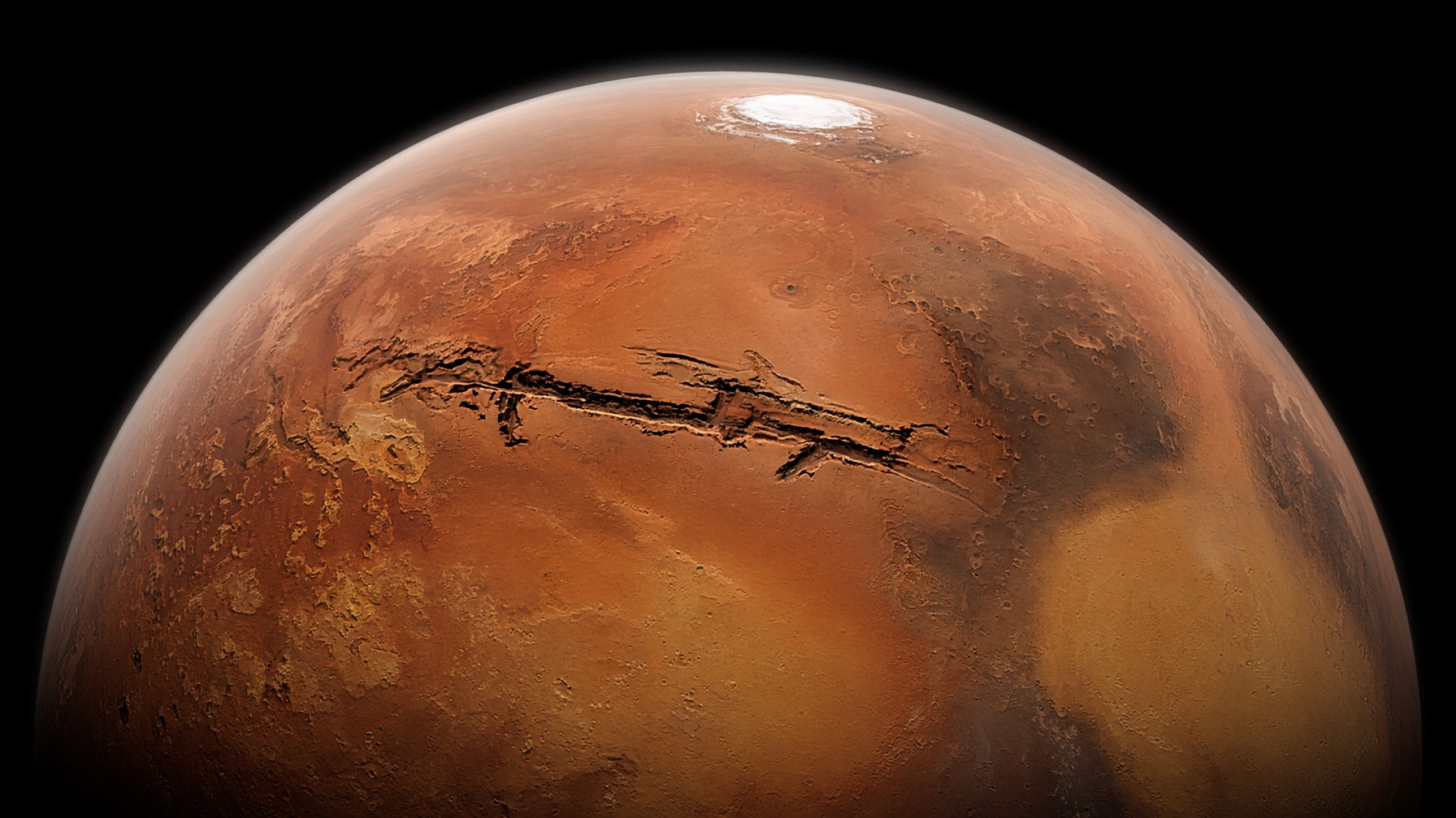 Mars from high orbit: a rust-red globe against black space, Valles Marineris cutting a dark scar across the equator.