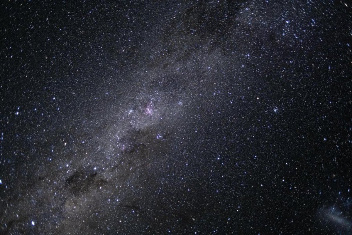 A dense star field over a dark horizon — the view this desk argues we have to reach.